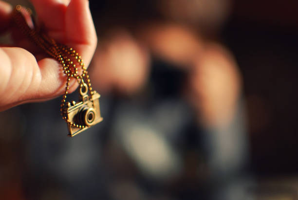 Hand holding a photo camera shaped pendant