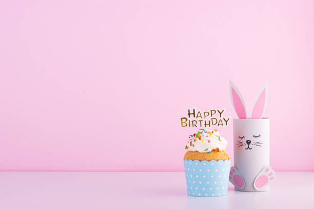 cute paper rabbit and a delicious beautiful cupcake cake for a birthday on a pink background - cupcake birthday birthday cake first place imagens e fotografias de stock