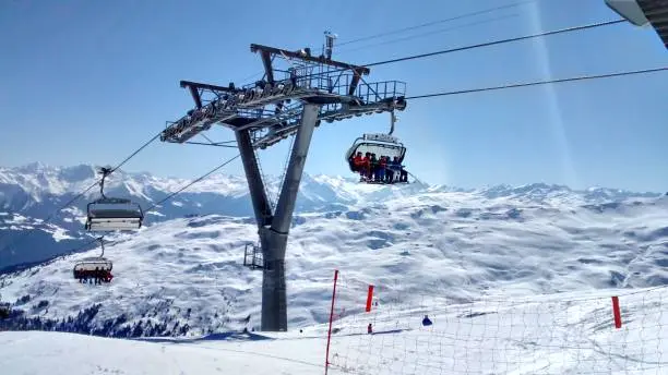 Chairlift in Austria with views of snow-capped mountains and blue skies