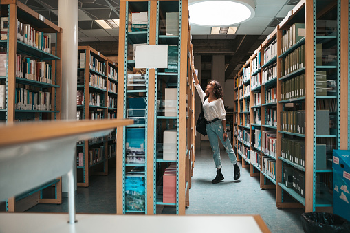 Young student choosing books on the bookshelf