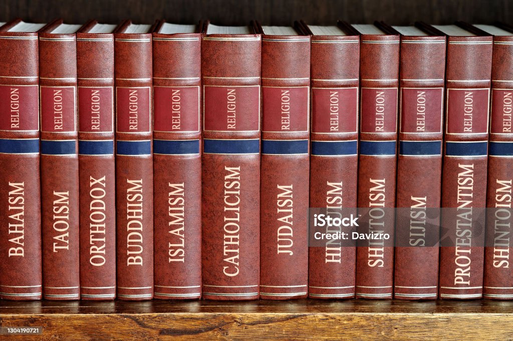 Collection of books of various religions on a wooden shelf Collection of books arranged in a row of various religions bound in brown leather on a wooden shelf Religion Stock Photo