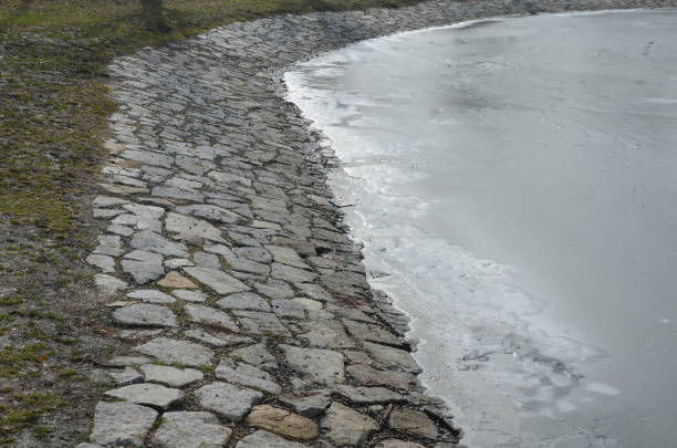 murs en pierre d’un réservoir d’eau ou d’un quai, d’une berge ou d’un étang, fortifiés de pierre de carrière de granit en pente vers l’eau. réservoirs de feu et de rétention de plage en pierre - retention pond photos et images de collection