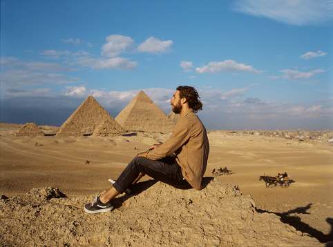 Young man sitting in the desert near the Giza pyramids