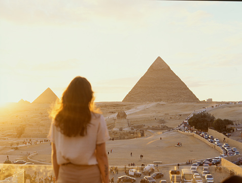 Young Caucasian woman standing on the  terrace on the  background of Giza pyramids