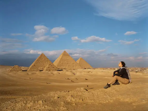 Young woman sitting in the desert near the Giza pyramids