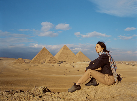 Young woman sitting in the desert near the Giza pyramids
