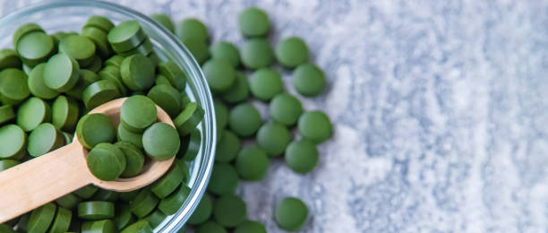 зеленые таблетки хлореллы и спирулины. селективный фокус - ground green wheatgrass isolated стоковые фото и изображения