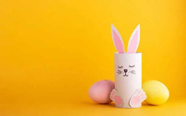 Photo of cute Easter bunnies made of paper with colorful Easter eggs