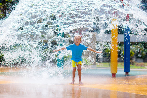 kind spielt unter spitze eimer im wasserpark. - amusement park family water slide child stock-fotos und bilder