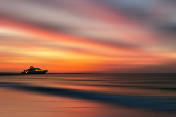 tramonto colorato con yacht sulla linea dell'orizzonte nel bellissimo mare del golfo, effetto motion blur con zoccoli e onde. tempo di vacanza per rilassarsi e godersi la vita. - dubai yacht luxury marina foto e immagini stock