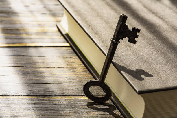 木製テーブルの上のヴィンテージキーとハードバックブック - secrecy ストックフォトと画像