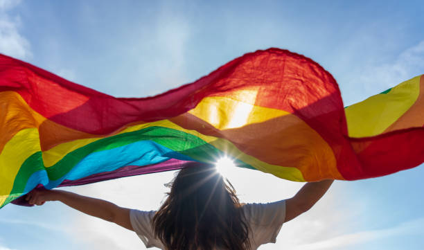 junge frau winkt lgbti flagge - lesbian gay man rainbow multi colored stock-fotos und bilder