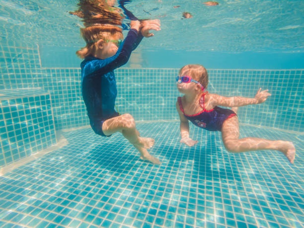 istock Kids having fun playing underwater in swimming pool on summer vacation 1304195712