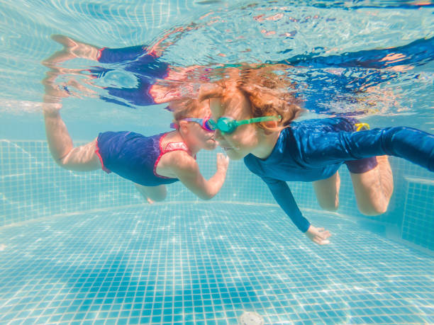 istock Kids having fun playing underwater in swimming pool on summer vacation 1304195714