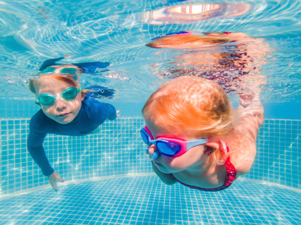 istock Kids having fun playing underwater in swimming pool on summer vacation 1304195729