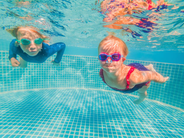 istock Kids having fun playing underwater in swimming pool on summer vacation 1304195730