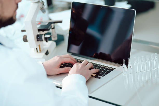 science lab technician using a laptop in the lab stock photo