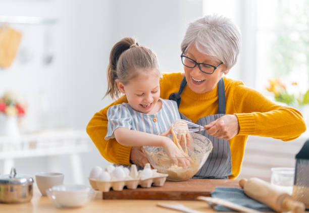 family are preparing bakery together Happy loving family are preparing bakery together. Granny and child are cooking cookies and having fun in the kitchen. granddaughter stock pictures, royalty-free photos & images