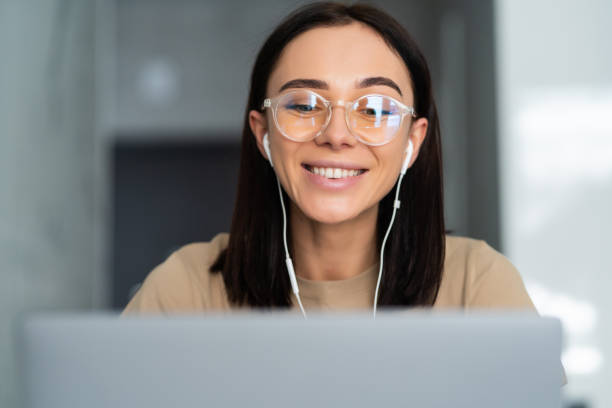 istock Young woman working remotely from home office on couch in kitchen behind laptop internet in headphones. Lifestyle communication work. 1304197694