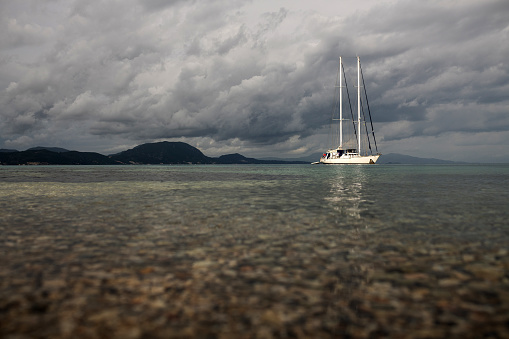 Corfu, Greece: A sailboat is anchored off the coast of Greece on a cloudy day.