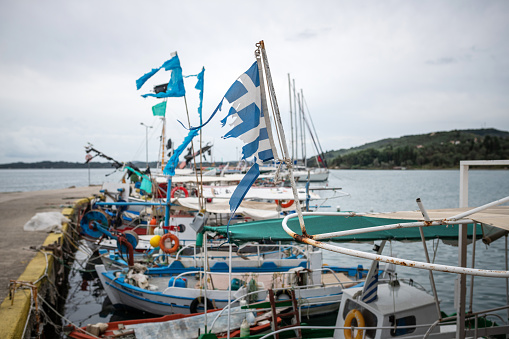 Corfu, Greece: Fishing boats are anchored in the harbor of Petriti with torn flags.