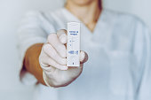 A nurse wearing latex gloves holds a covid-19 antigen test that has come back negative