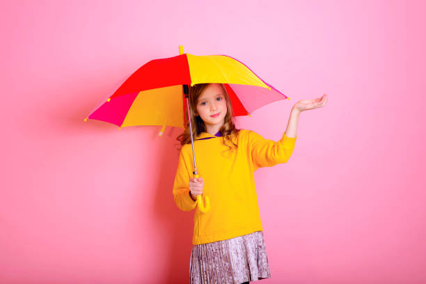 istock Girl is hiding under a colored umbrella on a pink background. 1304202673