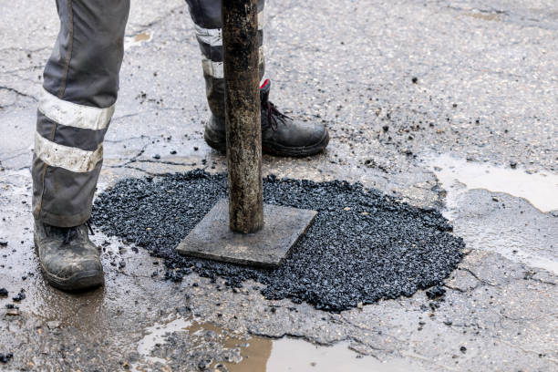 worker pushing bitumen asphalt in the hole. road repair and maintenance stock photo