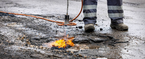 istock road worker prepare pothole with gas torch flame for repairing. copy space 1304206437