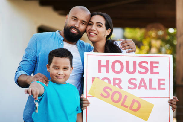 Home is not a place, its a feeling Shot of a smiling young family of three outside beside a sold sign with the boy holding a set of keys in their new home house for sale by owner stock pictures, royalty-free photos & images