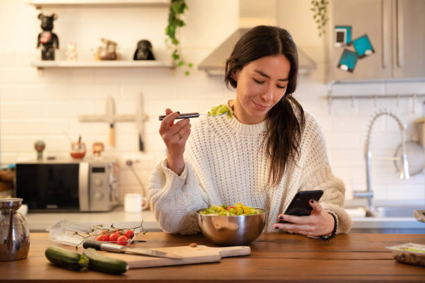 istock Young Women Eating and Using Smartphone 1304210546