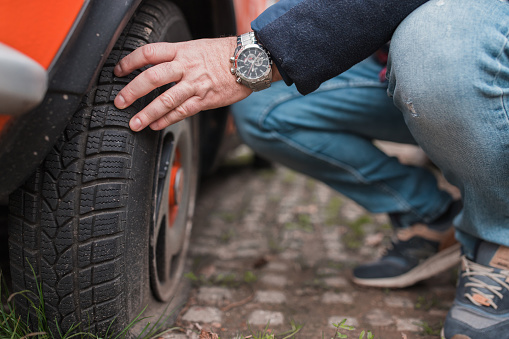 Man checking his car tires by hand