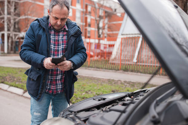istock Man standing by an open hood and text messaging with car mechanic 1304212210