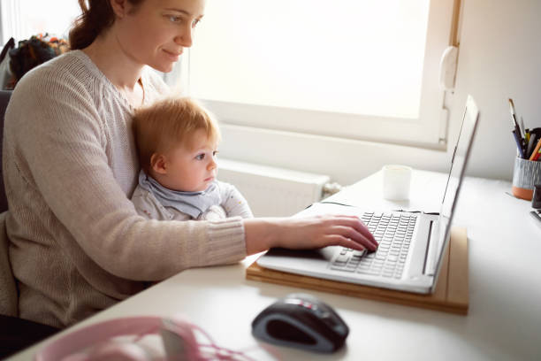 istock Multi-tasking mother holding her baby boy and working on the laptop 1304213687