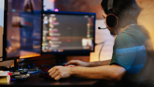 adolescente jugando juegos multijugador en pc de escritorio en su habitación oscura - servicio federal de protección fotografías e imágenes de stock