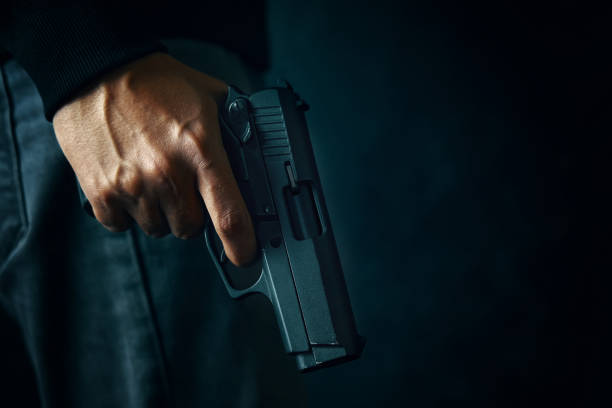 istock Criminal with revolver on dark background. 1304217383