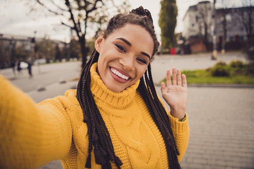 Retrato de la joven hermosa y atractiva chica afro sonriente alegre tomando selfie diciendo hola al aire libre photo