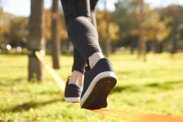 A woman is trying to walk on the tightrope,and a man is holding her hand to keep her balance