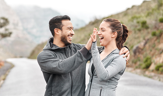 Shot of a sporty young man and woman giving each other a high five outdoors