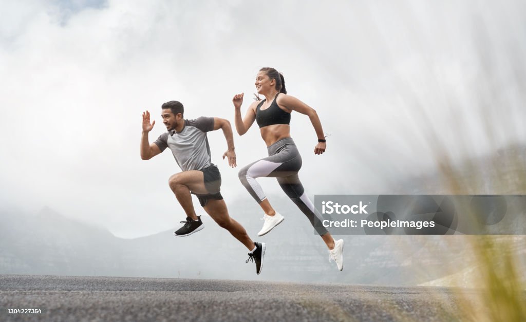 Started with a mile, now we're at marathons Shot of a sporty young man and woman running together outdoors Running Stock Photo