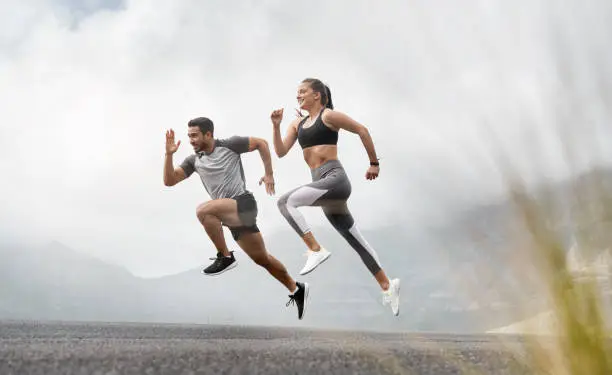 Shot of a sporty young man and woman running together outdoors