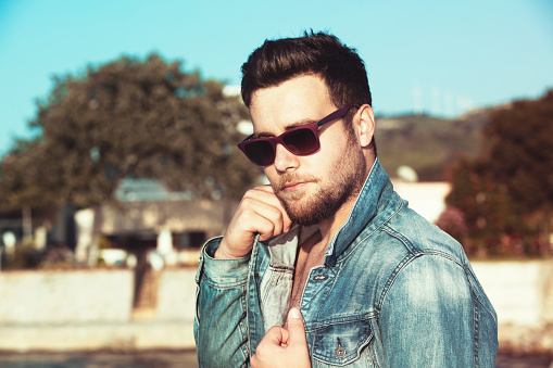 Cool handsome young man wearing jeans jacket and sunglasses