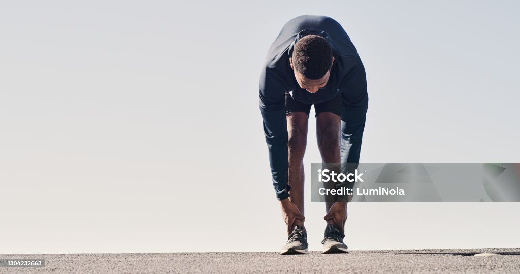 Increased flexibility helps us to perform better Shot of a man stretching while out on a mountain road for a run Stretching Stock Photo