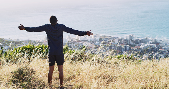Shot of a man standing with his arms outstretched against a city background