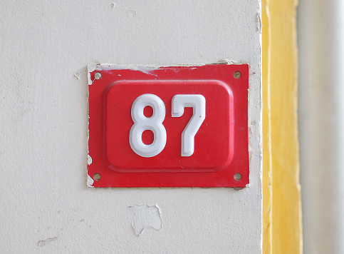 Red house number 87 on the wall