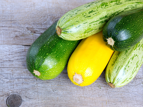 Zucchini on wooden background. Yellow and green zucchini. Vegetable marrow courgette or zucchini. Harvest courgette organic ingredient.