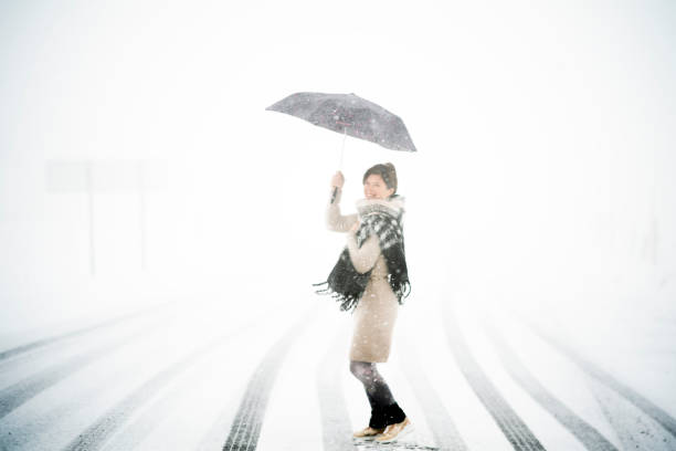 istock A smiling woman with an umbrella under the snow 1304243834