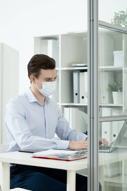 istock Young businessman in protective mask and formalwear networking in office 1304246509