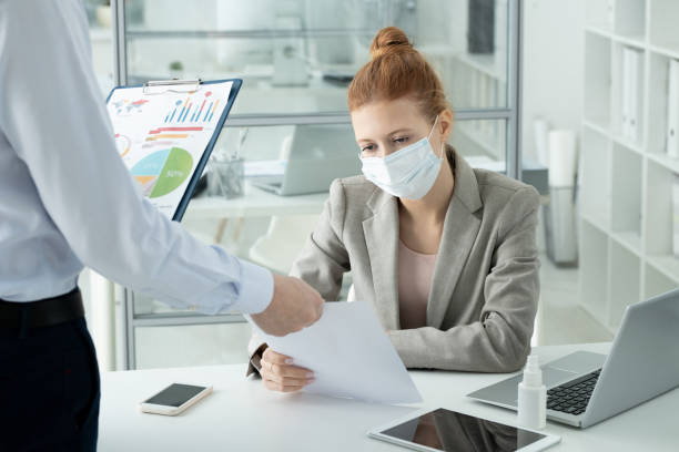 istock Young serious female office worker looking through paper held by her colleague 1304246543