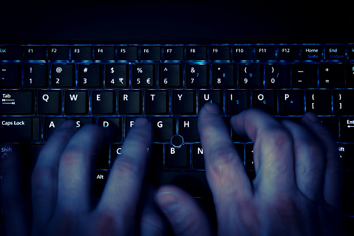 hands typing on keyboard in blue light with motion blur